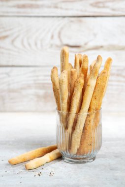 Grissini with herbs on a gray concrete background.
