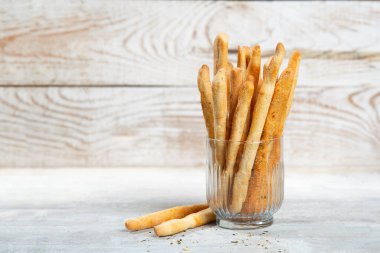 Grissini with herbs on a gray concrete background.