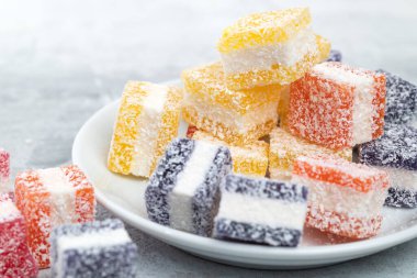 Cubes of multi-colored marmalade in powdered sugar on plate. The concept of baby sweets
