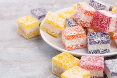 Cubes of multi-colored marmalade in powdered sugar on plate. The concept of baby sweets