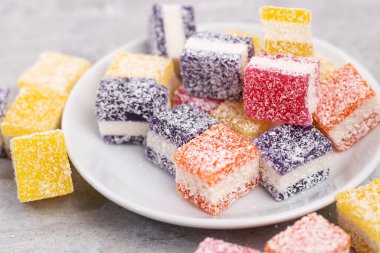 Cubes of multi-colored marmalade in powdered sugar on plate. The concept of baby sweets