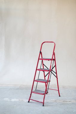 İçerideki beton duvarın önünde kırmızı merdiven yapım aşamasında.