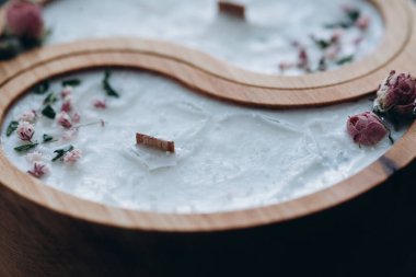 El yapımı aroma konsepti. Ahşap yin ve yang şeklinde soya mumu ve yakın plan balmumu kokulu kuru çiçekler.