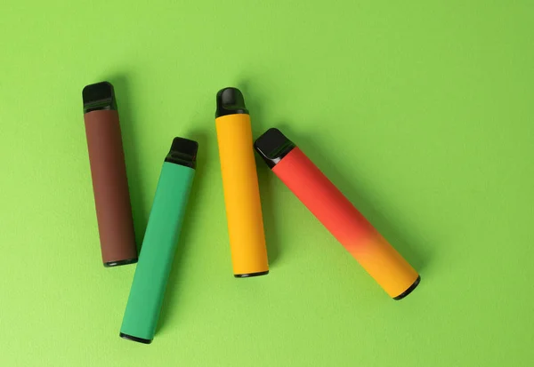 一套绿色背景的彩色一次性电子香烟 现代吸烟的概念 顶部视图 — 图库照片