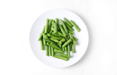 Fresh chopped green beans in a round plate, on a white background. top view