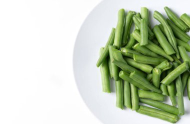 Fresh chopped green beans in a round plate, on a white background. top view