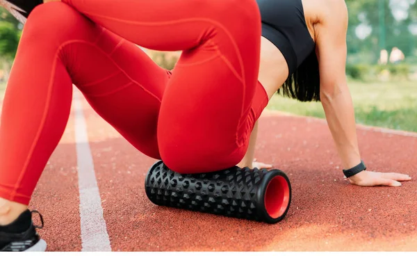 Theme sport and rehabilitation sports medicine. Beautiful strong slender Caucasian woman athlete uses massage roller to workout to remove pain, stretch and massage muscles.