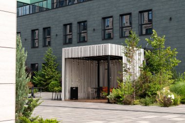 Modern smoking zone outside. business building, wooden gazebo with chairs. Green zone. Modern business center