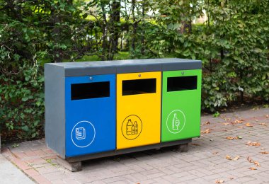 Parkta atık ayıklamak için üç farklı çöp konteynırı. Plastik için sarı, cam için yeşil, kağıt için mavi. Çöplerin ayrıştırılması ve sıralanması, çevre kirliliği kavramı.