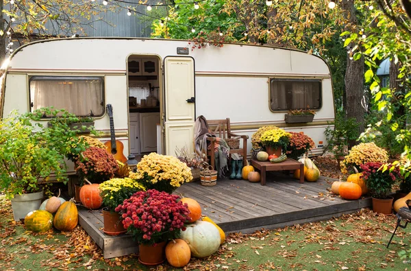 Mobile home van with terrace in autumn, mobile home, orange fallen leaves. autumn decor, pumpkins