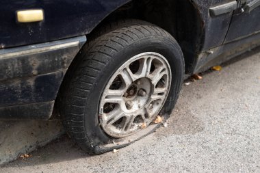 Yakın çekim hasarlı lastik. Araba lastiği sızıntısı. Lastik patlamış, onarılmayı bekliyor. Terk edilmiş araba otoparkta..