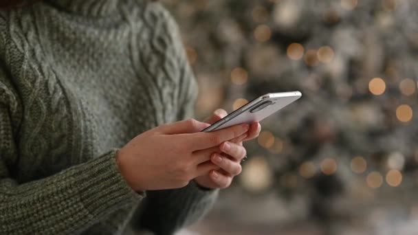 年轻女人用手机庆祝圣诞节 女性手牵着智能手机在网上留言 圣诞祝福 侧视图 — 图库视频影像