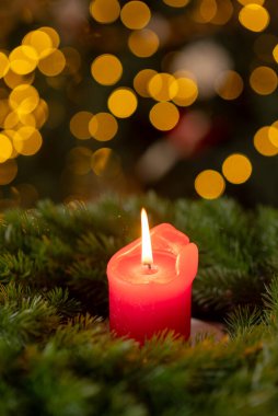 Noel 'den önce, köknar dallarından süslenmiş, ahşap pencere pervazında yanan kırmızı bir mumla süslenmiş bir çelenk..