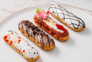 Beyaz tabakta orijinal krema dekoru olan nefis Fransız ekleriydi. Lezzetli tatlı profiterolleri 