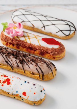 Beyaz tabakta orijinal krema dekoru olan nefis Fransız ekleriydi. Lezzetli tatlı profiterolleri 