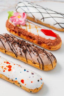 Beyaz tabakta orijinal krema dekoru olan nefis Fransız ekleriydi. Lezzetli tatlı profiterolleri 