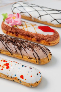 Beyaz tabakta orijinal krema dekoru olan nefis Fransız ekleriydi. Lezzetli tatlı profiterolleri 