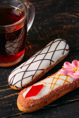 Koyu ahşap arka planda orijinal krema dekoru olan nefis Fransız ekleriydi. Yakın plan. Lezzetli tatlı profiterolleri. Yüksek kalite fotoğraf