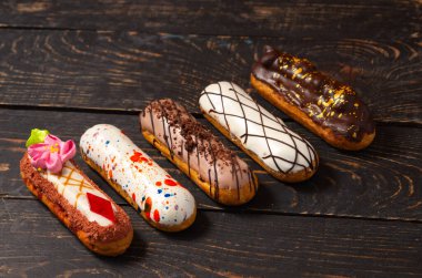 Koyu ahşap arka planda orijinal krema dekoru olan nefis Fransız ekleriydi. Yakın plan. Lezzetli tatlı profiterolleri. Yüksek kalite fotoğraf