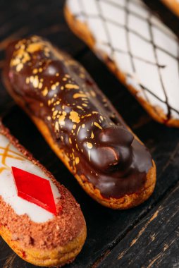 Koyu ahşap arka planda orijinal krema dekoru olan nefis Fransız ekleriydi. Yakın plan. Lezzetli tatlı profiterolleri. Yüksek kalite fotoğraf