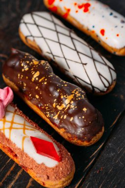 Koyu ahşap arka planda orijinal krema dekoru olan nefis Fransız ekleriydi. Yakın plan. Lezzetli tatlı profiterolleri. Yüksek kalite fotoğraf