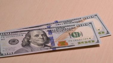 Masada bir Amerikan doları kağıt parası var. Masaya atılan bir sürü 100 dolarlık banknot..