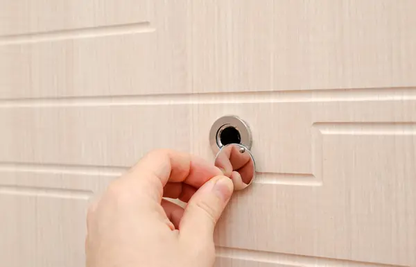 Hand near the door peephole on a new wooden door. High quality photo