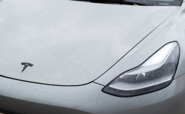 Kyiv, Ukrayna. 6 Nisan 2024. Tesla amblemi yakın çekimde. Arabanın kaputunun dış tarafında marka logosu ve su damlaları olan far..