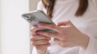 Kyiv, Ukrayna. 25 Nisan 2024. Yeni bir cep telefonu kullanan bir kadın, iPhone 15 akıllı telefonu yakın plan, cep telefonunu elinde tutuyor. mesaj gönderiliyor, kaydırılıyor