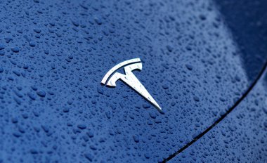 Kyiv, Ukrayna. 30 Mayıs 2024. Tesla amblemi, su damlalarıyla yakın çekim görüntüsünde. Mavi bir arabanın kaputunda marka logosu.. 