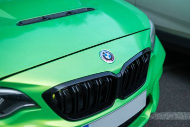 Canlı yeşil BMW M2 araba kaputu caddeye yakın park edilmiş, gösterişli parlak tasarım ve cesur tasarım.. 
