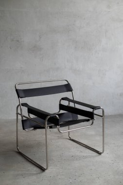 Beton bir arka planda minimalist bir iç iskeleti olan modern siyah deri sandalye.. 