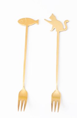 Two golden forks with decorative handles featuring cat and fish shapes, isolated on a white background, ideal for product or culinary design.  clipart