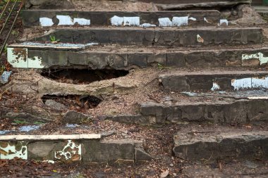 Büyük delikleri, çatlakları ve soyulmuş boyası olan eski beton merdivenler. Çürüme ve terk edilmişliği gösteriyor.. 