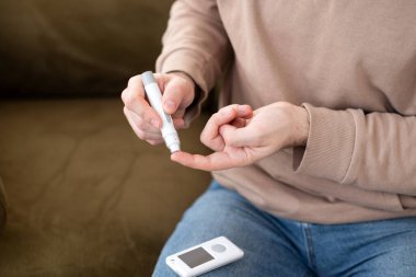 Evde kan şekerini glukometreyle ölçen bir adam var. Diyabet yönetimi, sağlık hizmetleri ve tıbbi izleme kavramı. 