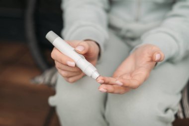 Kan şekeri seviyelerini kontrol etmek için glukometre kullanan bir kişi, sağlık hizmetleri, diyabet izleme ve kişisel bakım uygulamalarını vurguluyor 