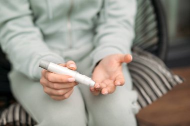 Kan şekeri seviyelerini kontrol etmek için glukometre kullanan bir kişi, sağlık hizmetleri, diyabet izleme ve kişisel bakım uygulamalarını vurguluyor 