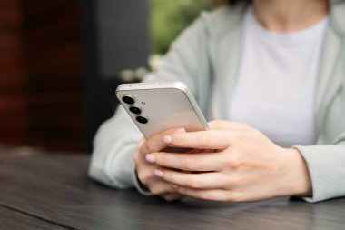 El ele tutuşmak ve modern bir akıllı telefonu açık havada kullanmak, günlük hayatta teknolojiyi ve bağlantıyı göstermek..