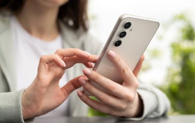 El ele tutuşmak ve modern bir akıllı telefonu açık havada kullanmak, günlük hayatta teknolojiyi ve bağlantıyı göstermek..