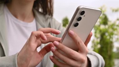 El ele tutuşmak ve modern bir akıllı telefonu açık havada kullanmak, günlük hayatta teknolojiyi ve bağlantıyı göstermek..