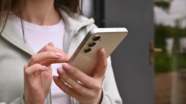 El ele tutuşmak ve modern bir akıllı telefonu açık havada kullanmak, günlük hayatta teknolojiyi ve bağlantıyı göstermek..