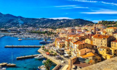 Calvi historic city center with sandy beach, historic houses and harbor with boats and yachts, Corsica, France, Europe.
