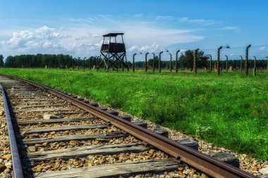 Auschwitz Holocaust Memorial  - view from inside the camp along rail tracks with Auschwitz II-Birkenau gatehouse in distance on an overcast day