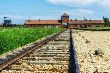 Auschwitz Holocaust Memorial  - view from inside the camp along rail tracks with Auschwitz II-Birkenau gatehouse in distance on an overcast day