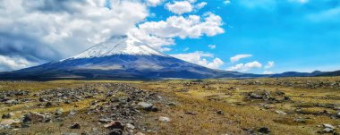 Ekvador, Cotopaxi, Cotopaxi Ulusal Parkı, karla kaplı Cotopaxi volkanı ve bulutlu bir gökyüzünün altındaki etrafındaki bozkırlar