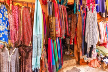 Fas 'ta bir turist dükkanının önünde renkli atkılar, iplikler ve dokulu duvarlarda boya pigmentleri olan canlı bir renk sahnesi. Marakeş 'in Medine' sinde.