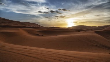 Sunset over the sand dunes in the desert. Arid landscape of the Sahara desert clipart