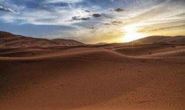 Çöldeki kum tepelerinin üzerinde gün batımı. Sahra Çölü 'nün ıssız manzarası