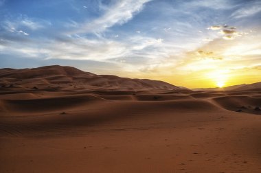 Çöldeki kum tepelerinin üzerinde gün batımı. Sahra Çölü 'nün ıssız manzarası