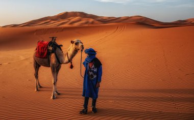 Turuncu bir kumul Erg African kum deniz, Sahra Çölü Merzouga, Fas, Kuzey Afrika, Afrika yakınındaki cephedeki deve ile berber adam